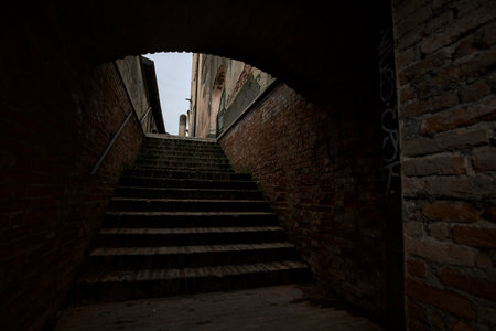 Staircase in a former fortification wall that leads to a cobbled alley bordered by a palaceの写真素材
