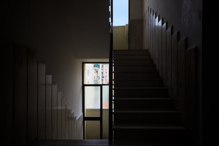 Staircase of a condominium counterlit by the sun coming from windows