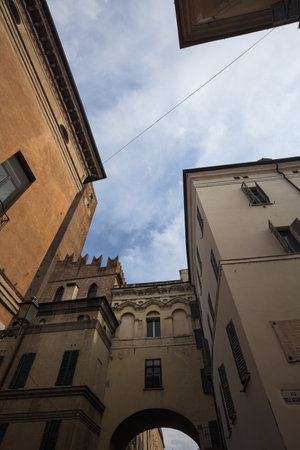 Facades of historical buildings and a brick tower standing tall with a partially cloudy sky as...