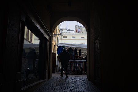 Covered passageway in the shade leading to an alley with a garment stallの写真素材