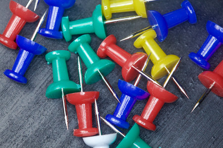 Colored pushpins on a black background seen up close
