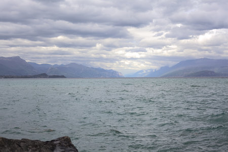 Mountain rough lake and an overcast sky with cliffs hit by the sunlight on the horizonの写真素材