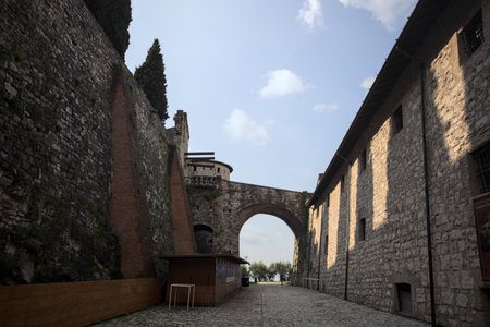 Cobbled path between a wall and a stone building in a castle with an arch in the backgroundの写真素材
