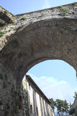 Stone arch of a bridge up above passing between walls with a partially cloudy sky as backgroundの写真素材
