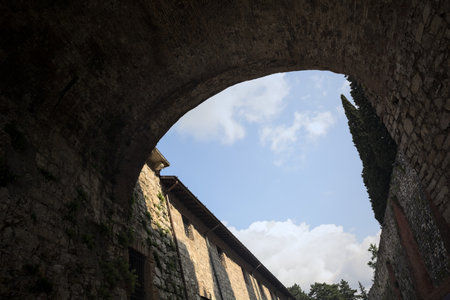 Stone arch of a bridge up above passing between walls with a partially cloudy sky as backgroundの写真素材