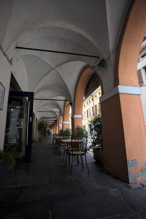 Porch in the shade by the edge of a street with tables and chairs on it on a sunny day in an Italian townの写真素材