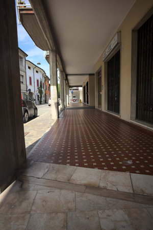 Modern porch under a building with shops closed by metallic shutters by the edge of a street on a sunny dayの写真素材