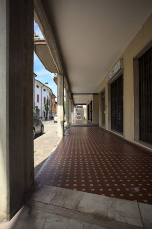 Modern porch under a building with shops closed by metallic shutters by the edge of a street on a sunny dayの写真素材