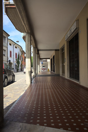 Modern porch under a building with shops closed by metallic shutters by the edge of a street on a sunny dayの写真素材