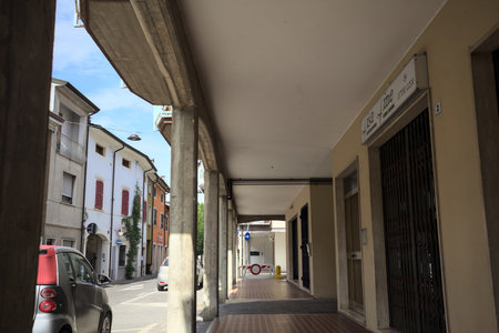 Modern porch under a building with shops closed by metallic shutters by the edge of a street on a sunny dayの写真素材