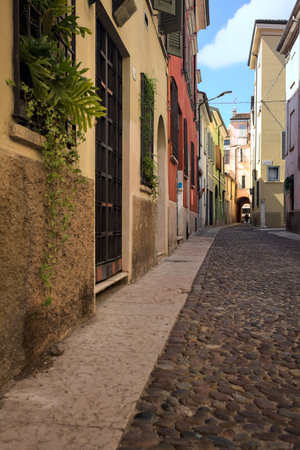 Cobbled street in the shade that leads to a covered passage under a building in an Italian town on a sunny dayの写真素材
