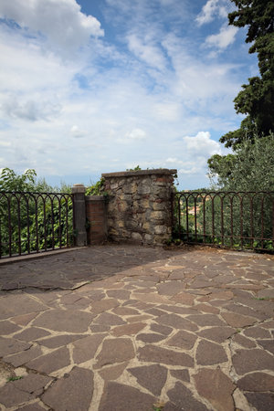 Terrace bordered by a rail with a tree with a cloudy sky aboveの写真素材