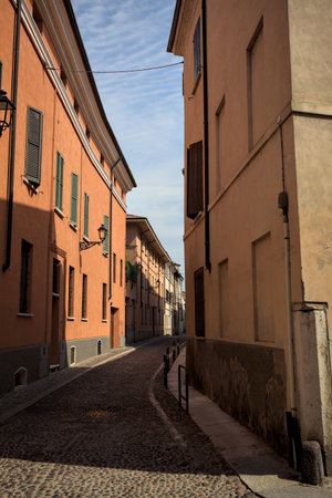 Access to a cobbled street partially in the shade with the road stretching in the distance between...