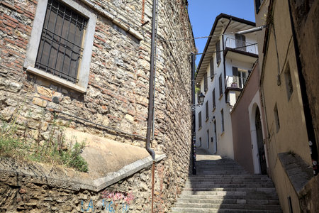 Climbing staircase between a stone facade and a building with street lamps on it seen on a sunny dayの写真素材