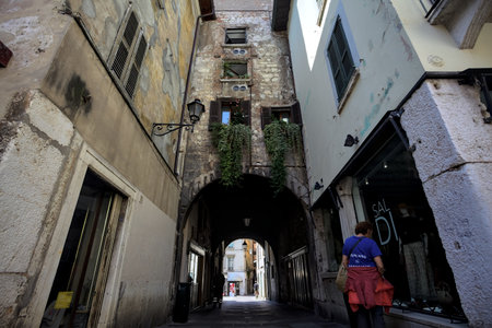 Covered archway passing under a building with hanging flowerpots by its windows on its facadeの写真素材