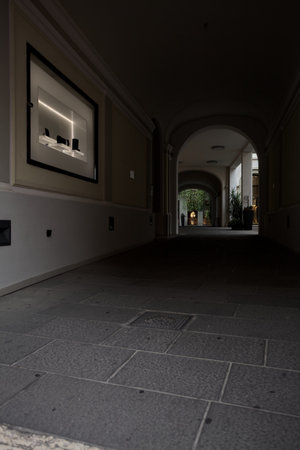 Covered alley with arches partially in the shade under a palace in an Italian town