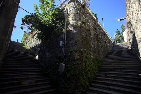 Stone staircases partially in the shade on a sunny day with a few plants on the walls in an Italian...