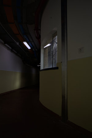 Dimly lit corridor by neon lights with tubes on its ceiling
