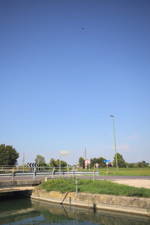 Road bridge over a diversionary channel with a trail next to it on a sunny day