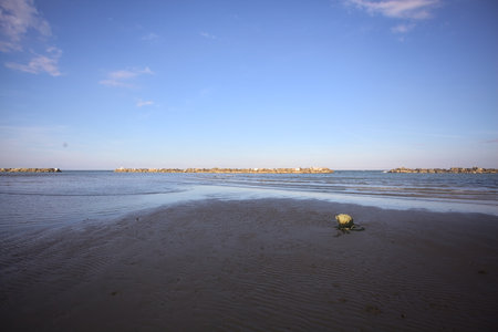 Buoy lying on the beach during a low tide at sunset