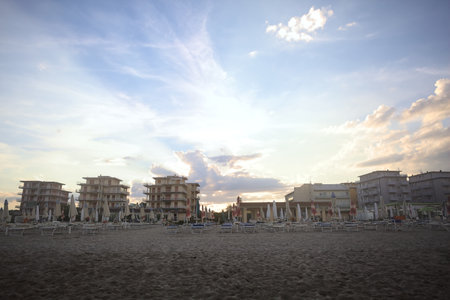 Buildings on an avenue next to a beach at sunset seen from behind an empty beach resortの写真素材