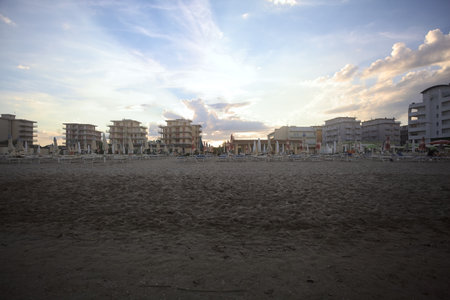 Buildings on an avenue next to a beach at sunset seen from behind an empty beach resortの写真素材