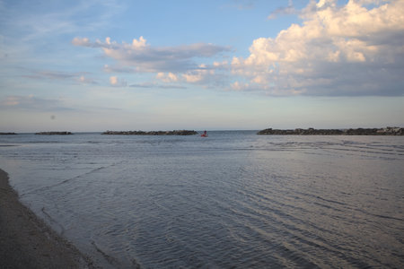 Beach during a low tide at sunset with a rock breakwater in the distance
