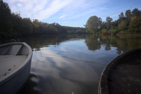 River bordered by enbankments with trees casted in the water and pontoons over it framing the scene