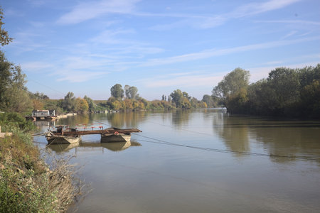 Platform on a raft made with two boats on a river with sky and shores casted in the water in the...