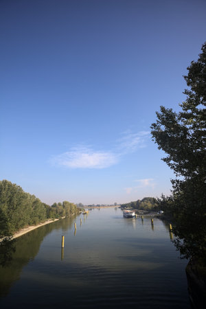Diversionary channel with poles in it and a moored boat with the sky reflected in the water and a...