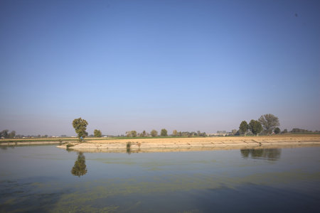 Fork in a diversionary channel made by a small island with a bridge and fields on the horizon on a...