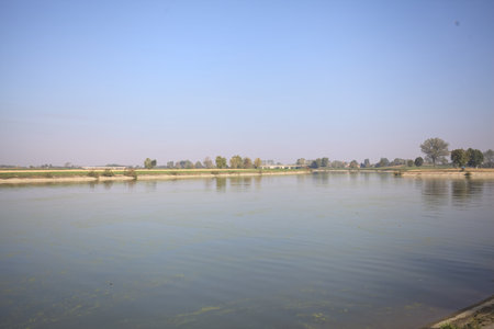 Fork in a diversionary channel made by a small island with a bridge and fields on the horizon on a sunny day in the countrysideの写真素材