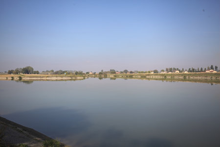 A diversionary channel made by a small island with fields on the horizon on a sunny day in the countrysideの写真素材