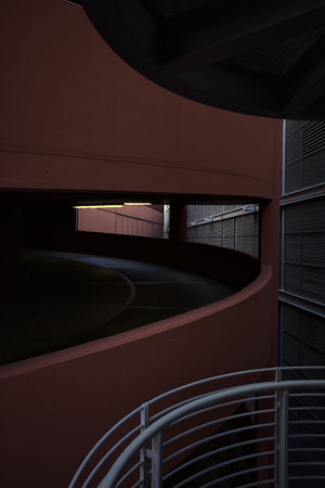 Spiral shaped ramp of a parking lot next to another building seen from a metallic staircase