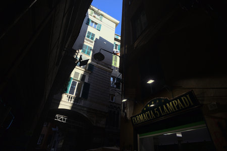 Facade of a tall historical building only partially under strong sunlightの写真素材