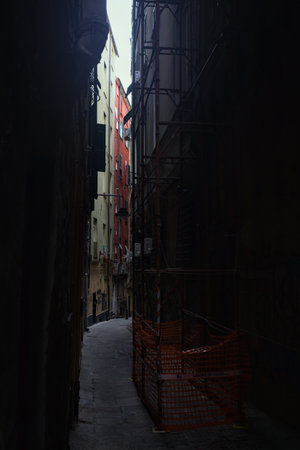 Alley in shade with a scaffolding in the middle of it and a clear sky shining aboveの写真素材