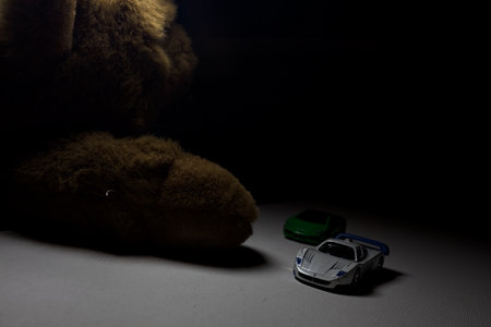 Mantua, Italy - 26TH OCTOBER 2025 - Hot Wheels and Matchbox replicas of a green Lamborghini Huracan and a white and blue Maserati MC12 pretending to have a race on a white surface with a teddy bear on the side of the trackのeditorial素材