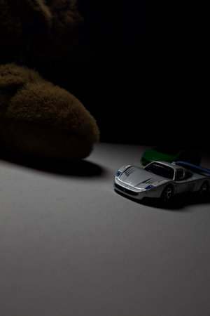 Mantua, Italy - 26TH OCTOBER 2025 - Hot Wheels and Matchbox replicas of a green Lamborghini Huracan and a white and blue Maserati MC12 pretending to have a race on a white surface with a teddy bear on the side of the trackのeditorial素材