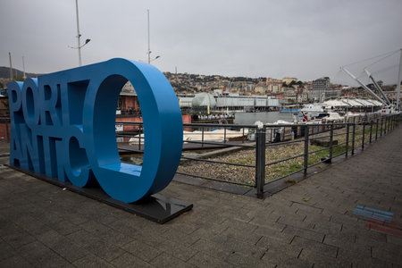 Genoa, Italy - 30TH OCTOBER 2025 - Seafront of the old pier named Porto Antico with moored boats and the aquarium building in the distance seen from the bank on a rainy dayのeditorial素材
