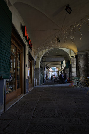 Genoa, Italy - 22ND NOVEMBER 2025 - Porchway with shops and hanging lights and people in the...