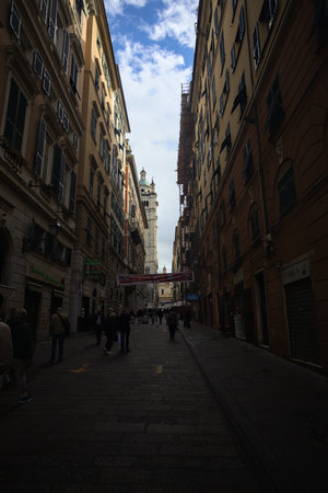 Genoa, Italy - 12TH NOVEMBER 2025 - San Lorenzo avenue in the Caruggi quarter with people walking by and opened shops and the Saints Ambrogio and Andrea church at the end of itのeditorial素材