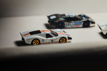 Mantua, Italy - 28TH DECEMBER 2025 - Hot Wheels replicas of two Ford GT40 Mark IV, one in a green race livery, another in white and orange Gulf race livery, and a GT40 in black and white race livery pretending to have a race on a race trackのeditorial素材