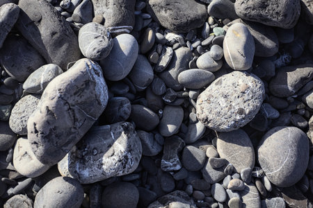 Pebbles on a beach in the sunlight seen from above and up close