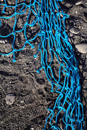 Blue fishing net lying on the sand of a beach seen up close