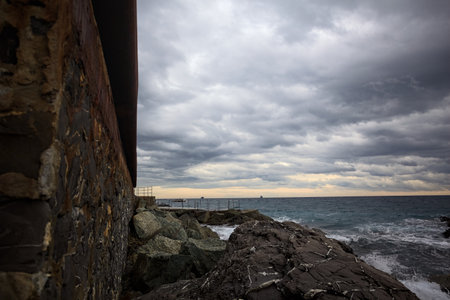 Stone wall on a cliff with rocks on the sea on a cloudy day at twilight