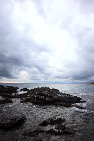 Rocks in the sea with ocean waves and a cloudy skyの写真素材