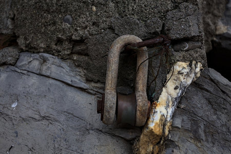 A rusty metal ring or lock hanging from a hook placed in a rock seen up closeの写真素材
