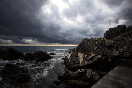 Breakwater with water crushing on its rocks on a cloudy day at twilightの写真素材