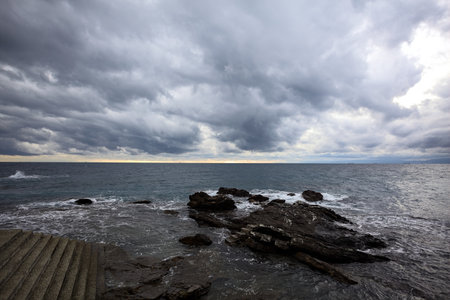 Staircase by the edge of a cliff alongside rocks on a cloudy day at twilight