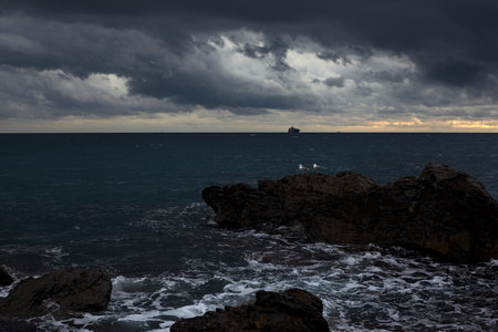 Breakwater with water crashing on its rocks on a cloudy day at twilightの写真素材